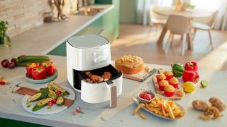 Philips Airfryer Essential Compact on a kitchen benchtop, surrounded by food
